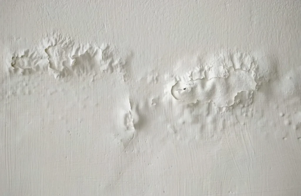 Damp staining and blistered paint on an internal wall caused by failed cavity insulation